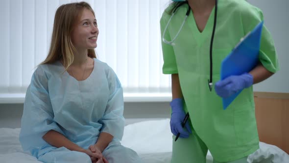 Teenage Girl Sitting on Bed in Hospital Ward As Doctor Entering Talking Smiling alt