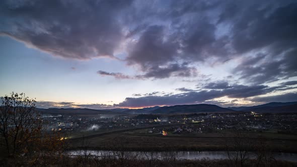 Small Town Turns on Lights Under Dark Evening Sky at Sunset alt