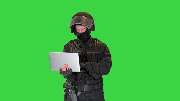 Masked Police Officer Using a Laptop Computer on a Green Screen Chroma Key alt