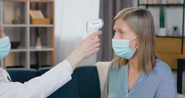 Medical Worker Checking Temperature Applying Non-Contact Infrared Thermometer to Patient's Forehead alt