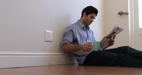 Man reading newspaper while having coffee alt