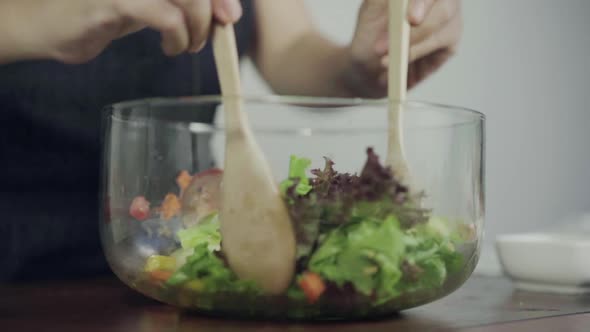 Health conscious young chief woman tossing a tasty organic green salad. alt