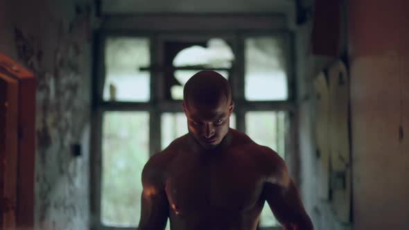 Athletic Man with a Naked Torso Walks Through a Destroyed Building