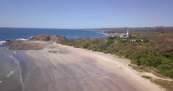 Aerial drone view of the beach, rocks and tide pools in Guiones, Nosara, Costa Rica alt