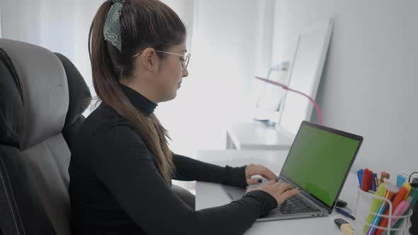 Young Girl Sitting at a Table and Typing Fast in Her Laptop alt