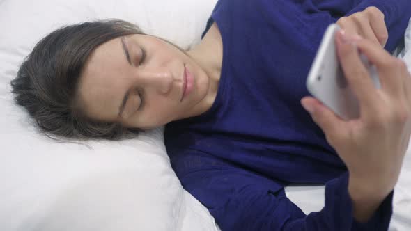 Hispanic Woman Using Smartphone at Night, Scrolling Screen alt