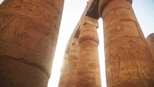 Massive pillars with intricate carved images and hieroglyphs in the Kamak Temple, Luxor, Egypt. Sun alt