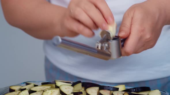Woman Presses Garlic with a Press alt
