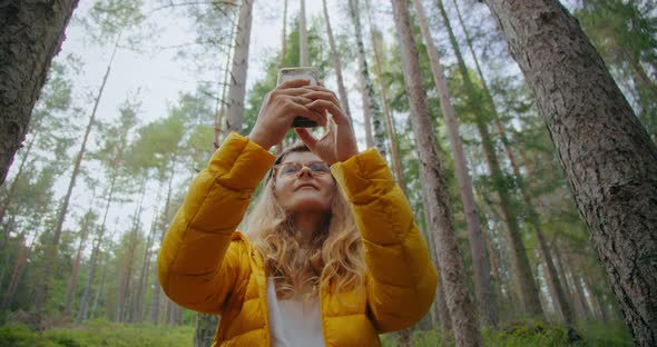 Young Woman in Forest Make Photos or Search Signal alt