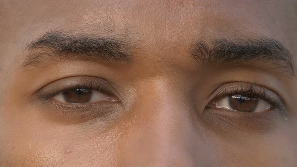 focus on young black african man opening his eyes and looking at camera alt