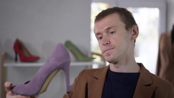 Closeup Portrait of Elegant Confident Gay Man Examining Purple Shoes in Shop in Slow Motion alt