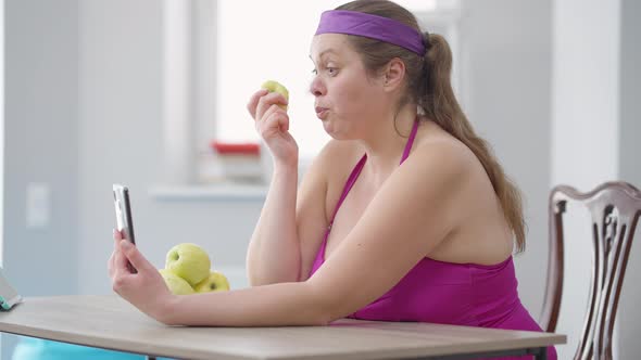 Side View of Plussize Caucasian Young Woman Eating Healthful Organic Vitamin Apple Looking at alt