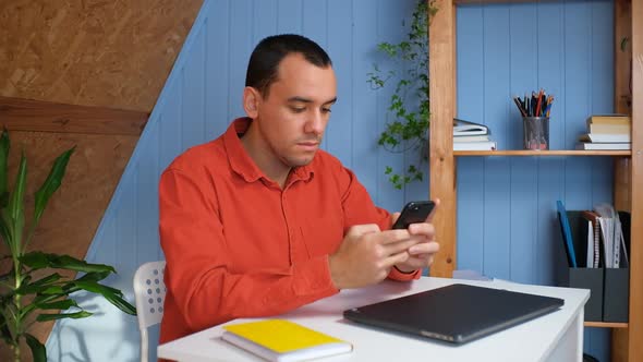 Young Man Holding Modern Smartphone Texting Message in Office