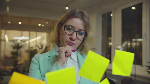 Female Manager Writing Ideas on Stickers in Office alt
