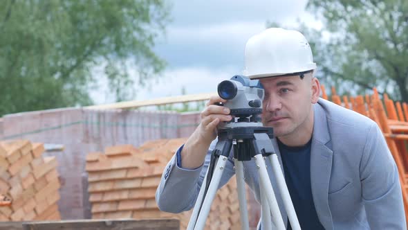 Foreman Amid Construction Looks Into the Device To Determine the Level and Vertical Horizon
