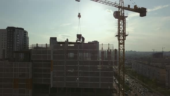 Raising the Camera Up Along a Building Under Construction with Empty Floor Spans and Workers on the