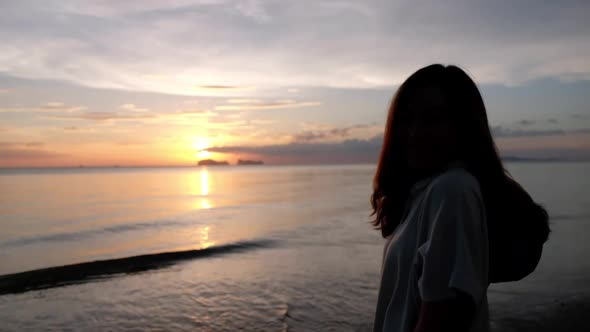 A woman walking on the beach before sunset