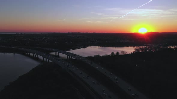 An aerial view over a parkway during sunset with a drone camera. The sun is on the horizon & the sun alt