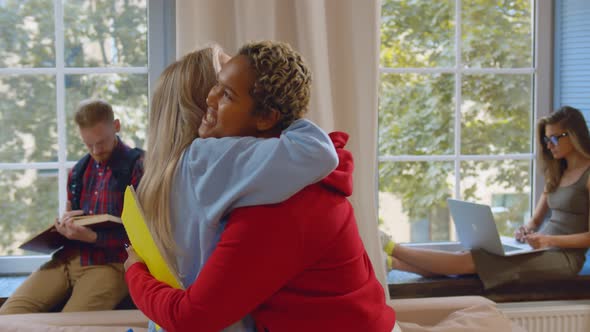 Cheerful Diverse Students Hugging and Smiling Meeting in College Common Room alt