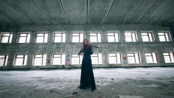 Young Woman Playing Violin in a Room with Graffiti on Walls.  alt