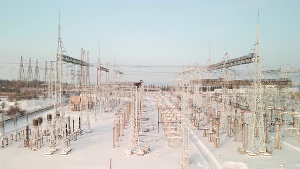 Aerial View of an Electrical Substation in Winter with High Pylons and Voltage Distribution Cables alt
