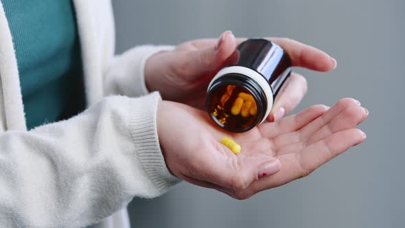 Closeup of Female Hands Holding Bottle with Pills alt