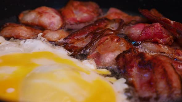 Frying crispy bacon and an egg in a pan. Cooking meat. alt