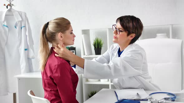 Young Girl Visiting Doctor Checking Thyroid Having Complaint During Appointment Medium Shot alt