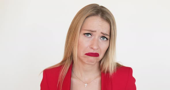 Grimacing Blonde Woman in Red Jacket.