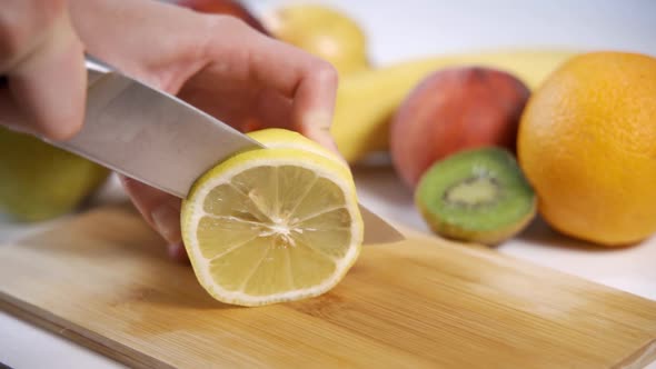 Closeup of Hand with Knife Cutting Lemon