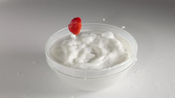 Slices of Strawberries Fall Into a Bowl of Milk