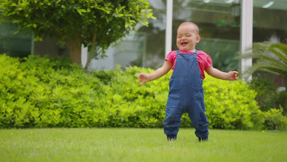 Close Up of Happy Girl Toddler Outdoor Takes the First Steps and Falls alt