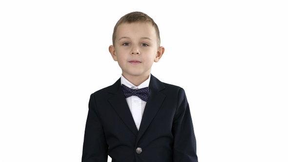 Little boy in a costume with a bow tie walking on white background alt