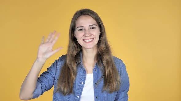 Pretty Woman Waving Hand To Welcome Isolated on Yellow Background alt