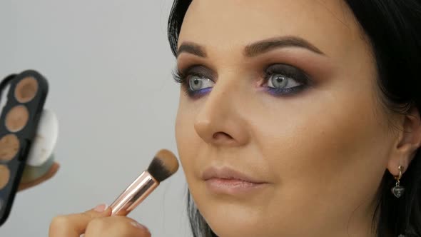 Stylist Makeup Artist Applies Foundation for Face with a Special Brush on the Face of Young alt