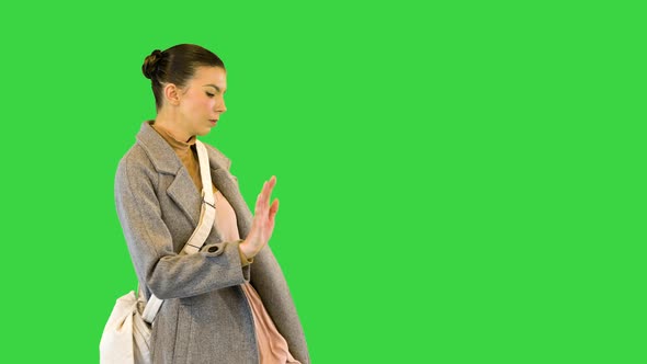 Young Woman in Grey Coat Stands Dancing on a Green Screen Chroma Key alt