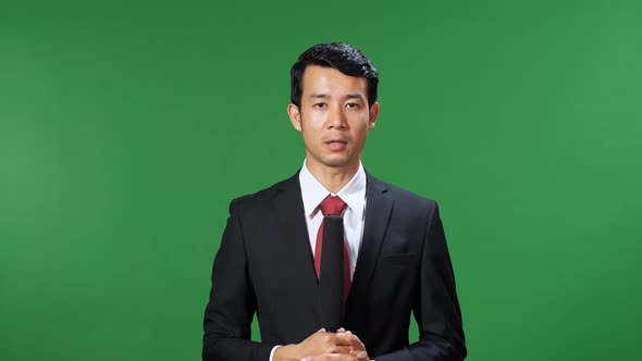 Asian Male Tv News Reporter In Formal Wear Talking On A Green Screen, Chroma Key alt