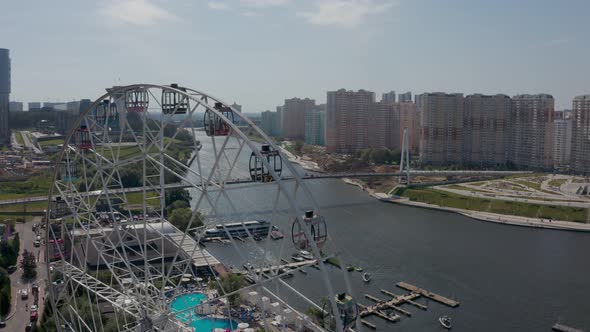 a Ferris Wheel on the River Bank with a Swimming Pool and a Beautiful Summer Landscape alt