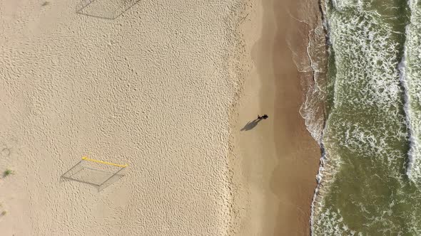 AERIAL: Top Shot of Young Couple Walking Holding Hand on Sunny Day on Sandy Beach