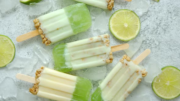 Lime and Cream Homemade Popsicles or Ice Creams Placed with Ice Cubes on Gray Stone Backdrop alt