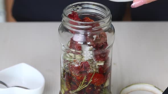 A Woman Lays Sun Dried Tomatoes In A Jar Of Olive Oil And Spices. Cooking Sun Dried Tomatoes alt