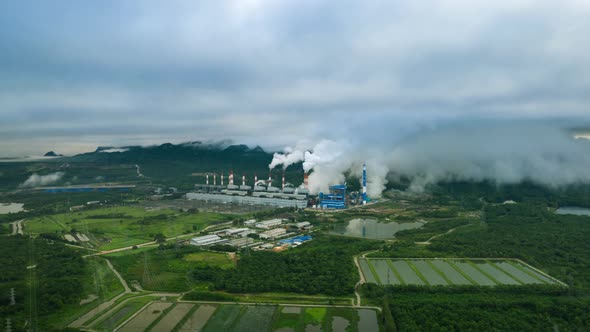 Aerial view over coal-fired power plant at sun dawn with smoke from cooling,
