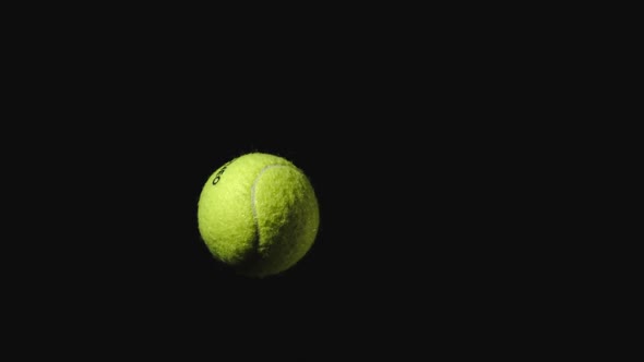 Tennis ball flies up and falls down on a black background
