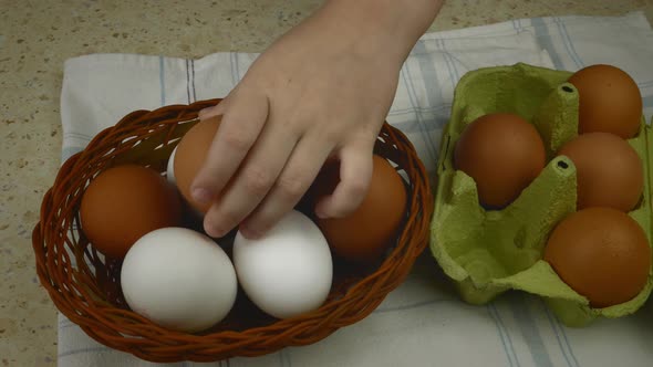 Closeup of a Child's Hand Transferring Eggs From a Container to a Basket