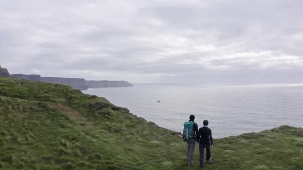 Aerial View of Beautiful Irish Cliffs Young Couple Walk Watch the Landscape Panorama Hug Each Other