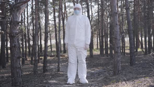 Conscious Caucasian Young Man in White Safety Suit Standing in Forest Next To Suburban Road and alt