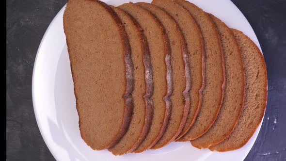 Sliced Dark Bread Rotates on a Plate Closeup