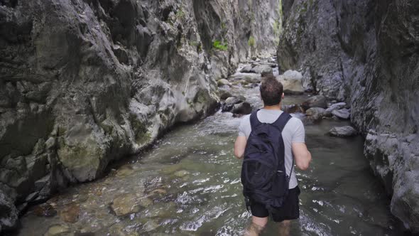 Young man walking in a flowing stream. Inside the canyon. alt
