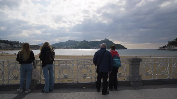 People admire majestic view of San Sebastian bay while on coastal pathway, gimbal motion alt
