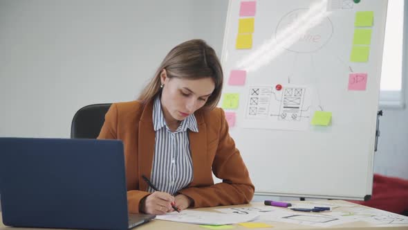 Woman Making Notes About New Application Project Sitting in Offi